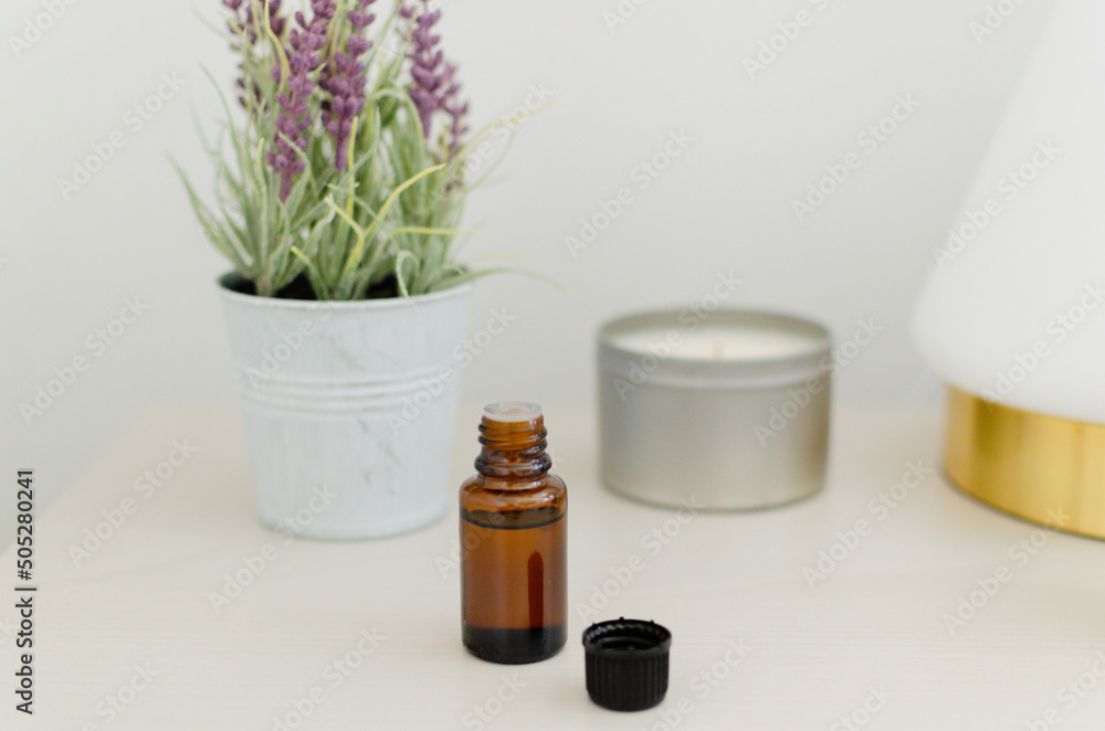 Self care with essential oil, candle and lavender plant on a bedside table