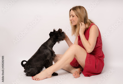 Young happy woman with her dog playing on a white background.