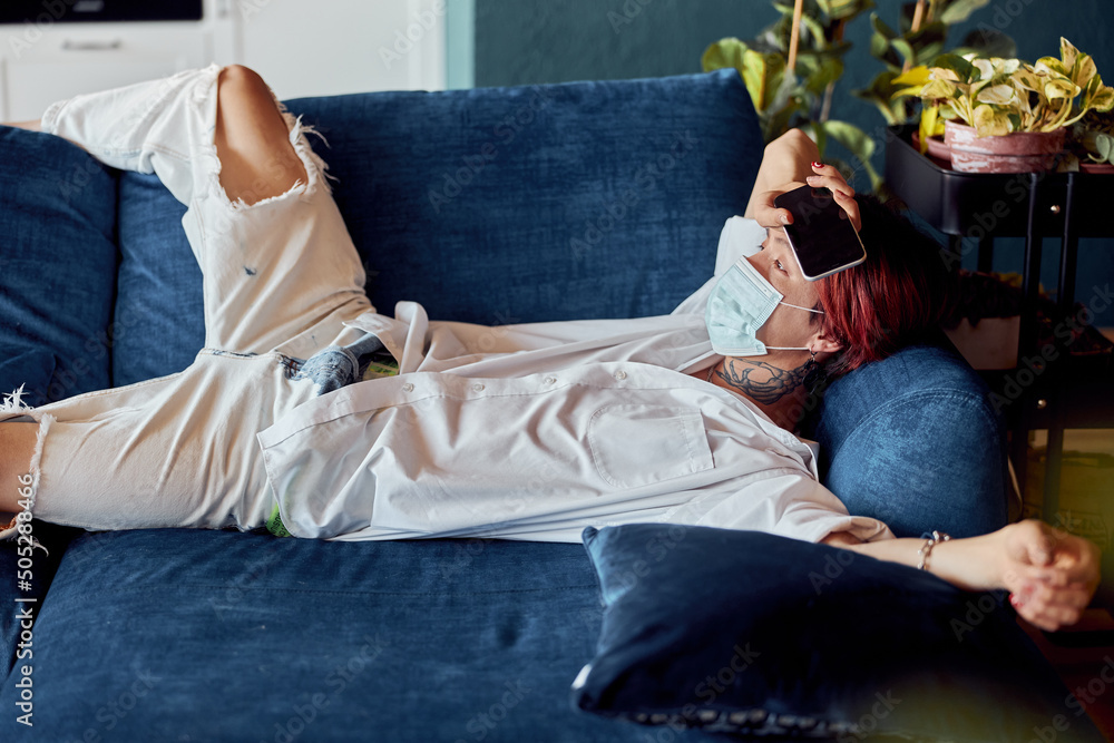 Obraz premium Asian man in medical mask enjoying rest on the sofa at flat