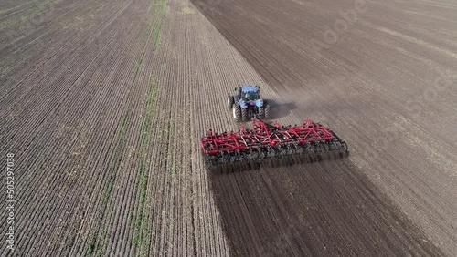 Agricultural tractor in the field fluff the earth. Aerial view 4k video