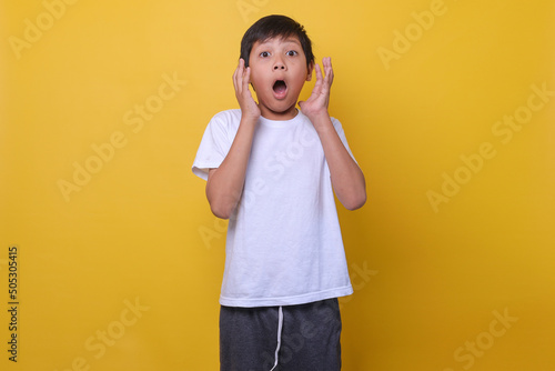 Foto Asian boy in a casual style feeling suprised on yellow background
