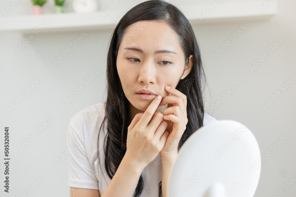 Dermatology, puberty asian young woman, girl looking into mirror, allergic when facial dirty and cosmetic, show squeezing pimple spot on her face. Beauty care from skin problem by acne treatment. Dermatology, puberty asian young woman, girl looking into mirror, allergic when facial dirty and cosmetic, show squeezing pimple spot on her face. Beauty care from skin problem by acne treatment.