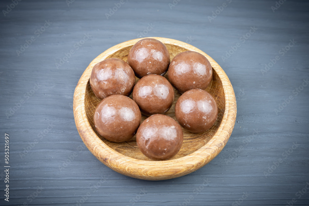 Obraz premium Chocolate candies in a wooden cup on a dark background (copy space).