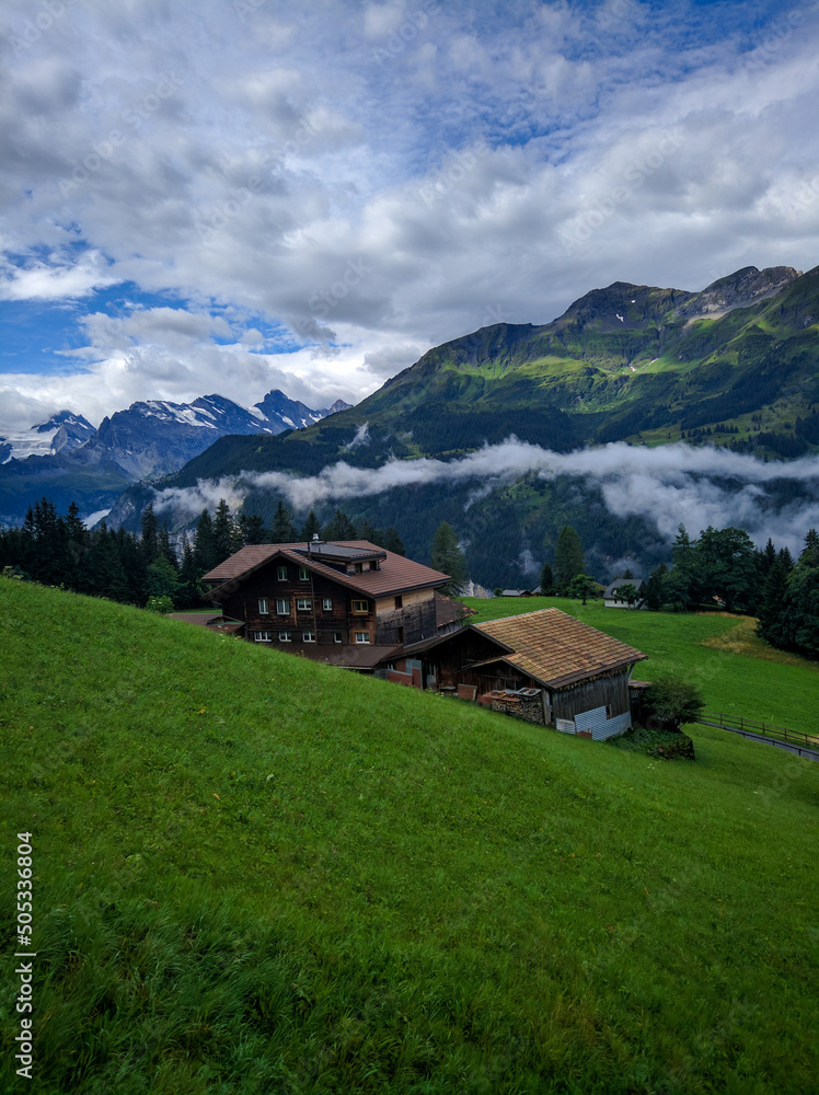 Fototapeta premium Lauterbrunnen, Switzerland - August 19, 2019: Beautiful view of the Alpine Lauterbrunnen valley with wooden chalets in the Jungfrau region. Vertical