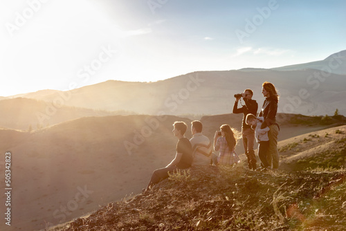 Big group of young peoples are relaxing in sunset mountains photo