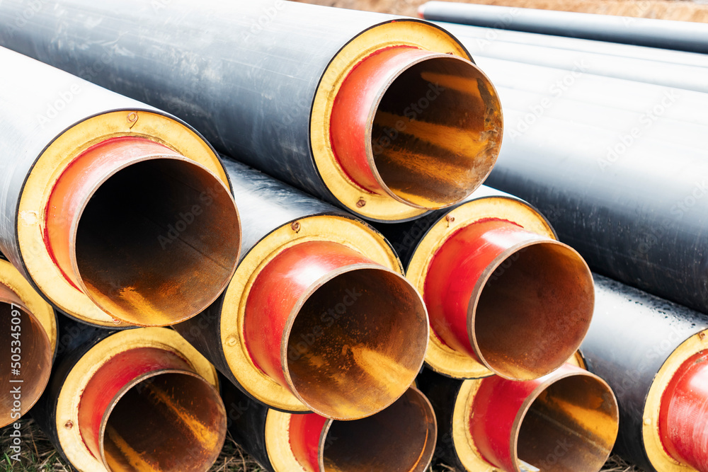 Insulated pipe. Large metal pipes with a plastic sheath at a construction site. Modern pipeline for supplying hot water and heating to a residential area. Insulated pipe. Large metal pipes with a plastic sheath at a construction site. Modern pipeline for supplying hot water and heating to a residential area.
