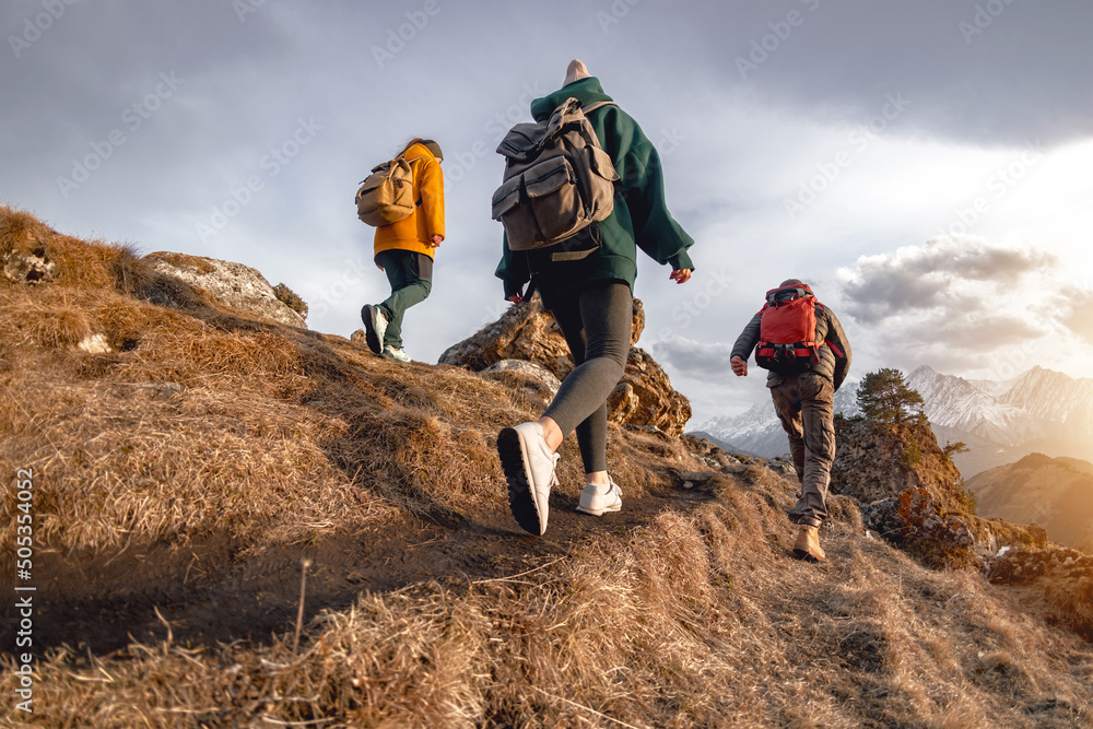 Young hikers with small backpacks walks in mountains - obrazy, fototapety, plakaty 