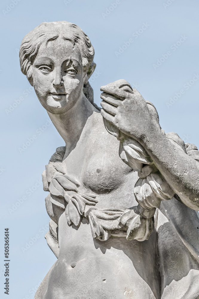 Ancient statue covered with moss and lichen of a sensual renaissance era woman in Potsdam city park, Germany, details, closeup.