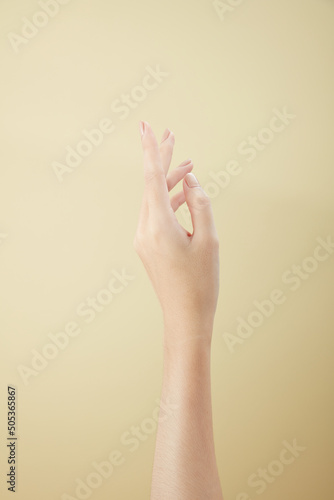 A front view of hand posing in beige background for cosmetic advertising