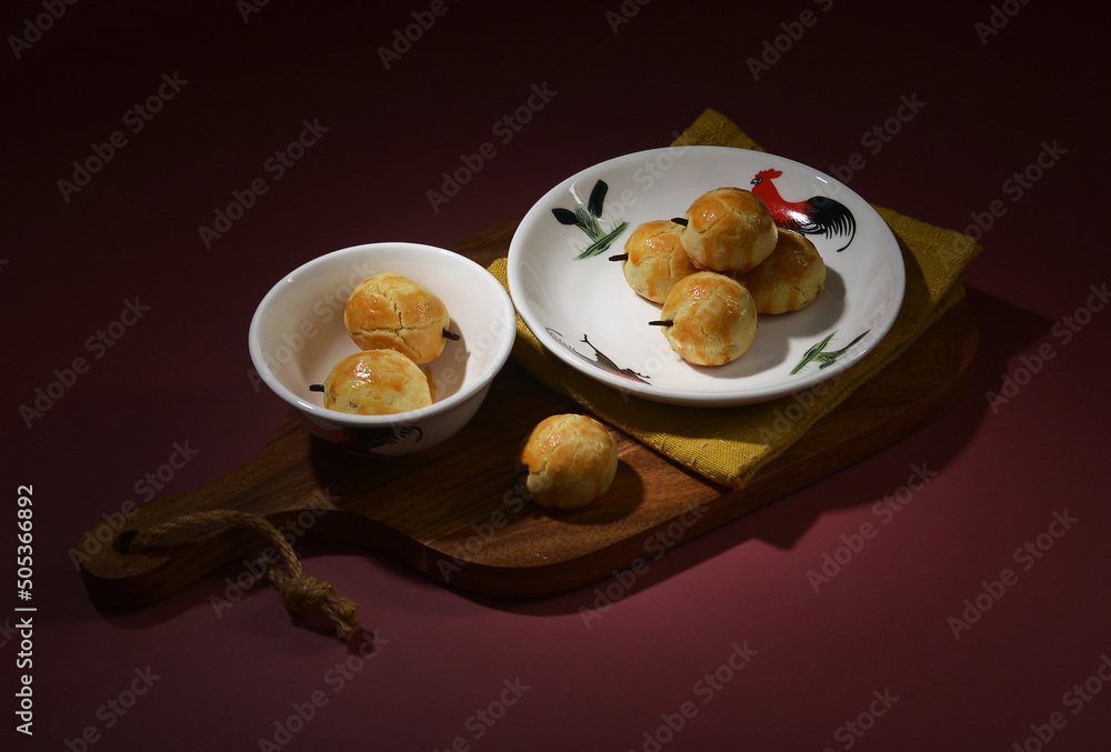homemade peranakan nonya pineapple fruit tart with clove in cock plate and bottle on traditional kampong red background halal cookies menu for Chinese new year and Malay raya festival homemade peranakan nonya pineapple fruit tart with clove in cock plate and bottle on traditional kampong red background halal cookies menu for Chinese new year and Malay raya festival