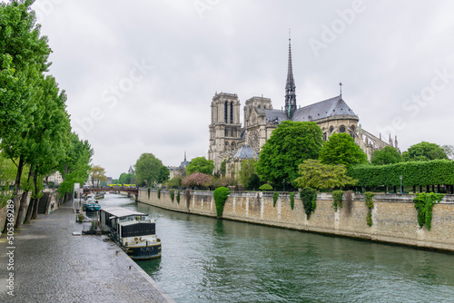 Lateral view of Notre-dame Cathedral by the Seine river on a cloudy day