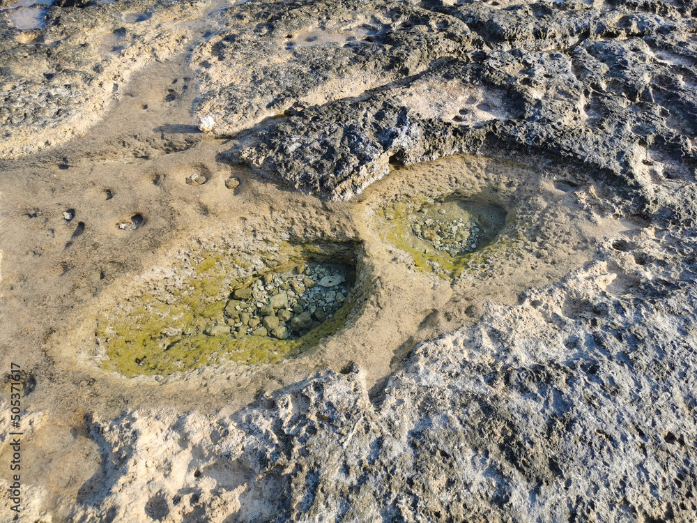 Obraz premium The coast of the Mediterranean Sea, clear water, long-hardened lava, in the recesses of which there is sea water. Background. It looks like an alien landscape.