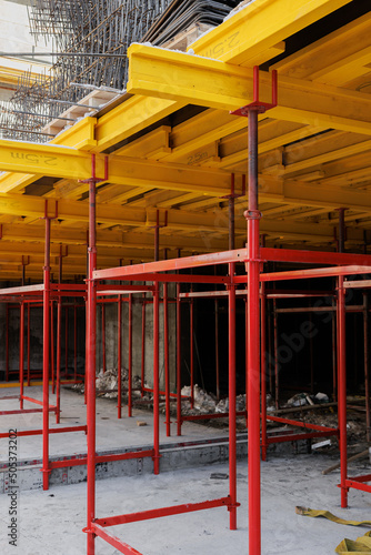 construction formwork for concrete pouring at construction site. Concrete slab construction. Plywood sheets, yellow timber beams and red steel supports.