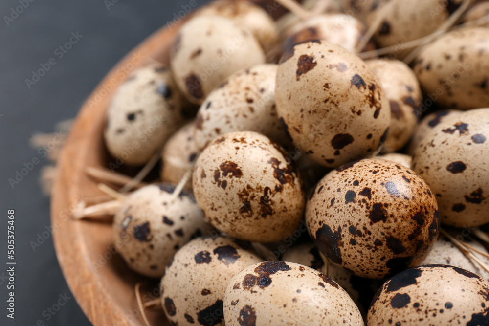 Bowl with quail eggs and straw on black table, closeup Bowl with quail eggs and straw on black table, closeup