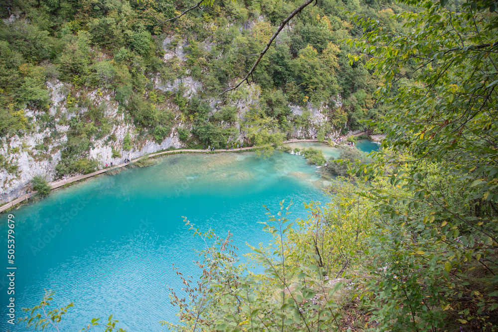 Plitvice Lakes National Park, Croatia, Europe: Panoramic view to one of the lower lakes with its beautiful turquoise water between steep slopes and a boardwalk leading around Plitvice Lakes National Park, Croatia, Europe: Panoramic view to one of the lower lakes with its beautiful turquoise water between steep slopes and a boardwalk leading around