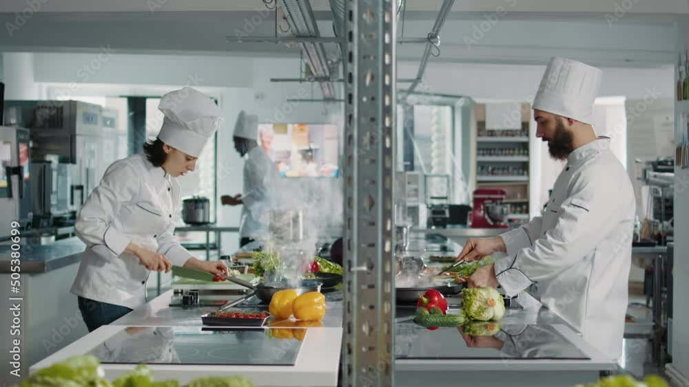 Team of cooks preparing fresh ingredients to follow culinary recipe, making gastronomic dish in authentic restaurant kitchen. People working as chefs cooking gourmet meal with vegetables. Team of cooks preparing fresh ingredients to follow culinary recipe, making gastronomic dish in authentic restaurant kitchen. People working as chefs cooking gourmet meal with vegetables.
