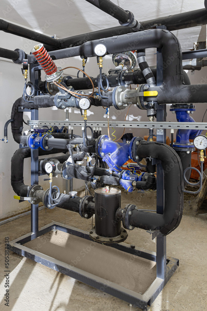 Obraz premium Industrial basement with heating pipes, pressure gauges, valves and heat exchangers