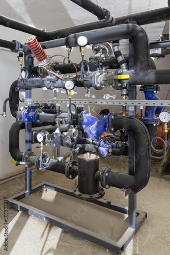 Industrial basement with heating pipes, pressure gauges, valves and heat exchangers