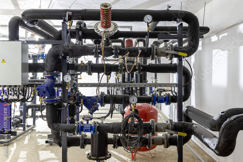 Industrial basement with heating pipes, pressure gauges, valves and heat exchangers