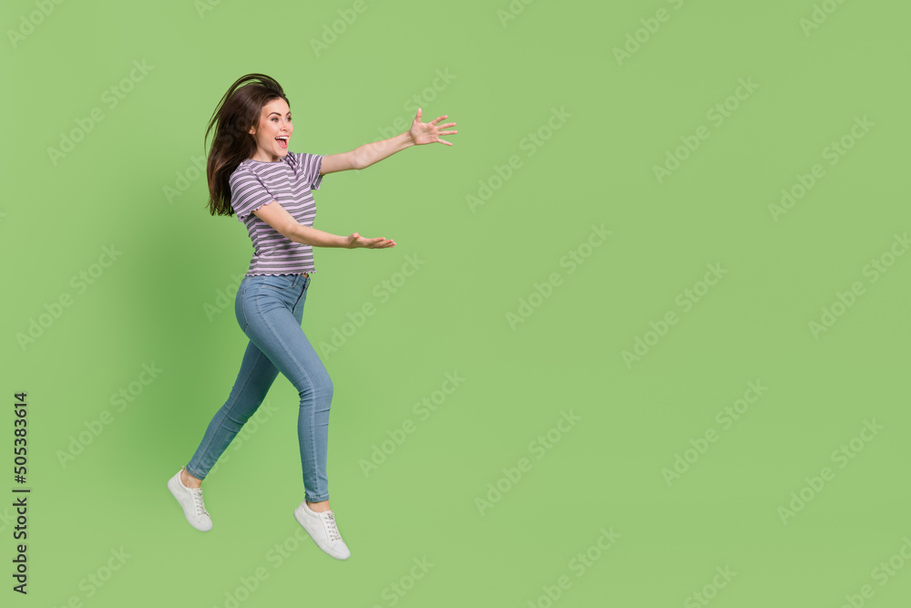 Full length body size view of attractive cheerful girl jumping catching ad copy empty space isolated on bright green color background Full length body size view of attractive cheerful girl jumping catching ad copy empty space isolated on bright green color background