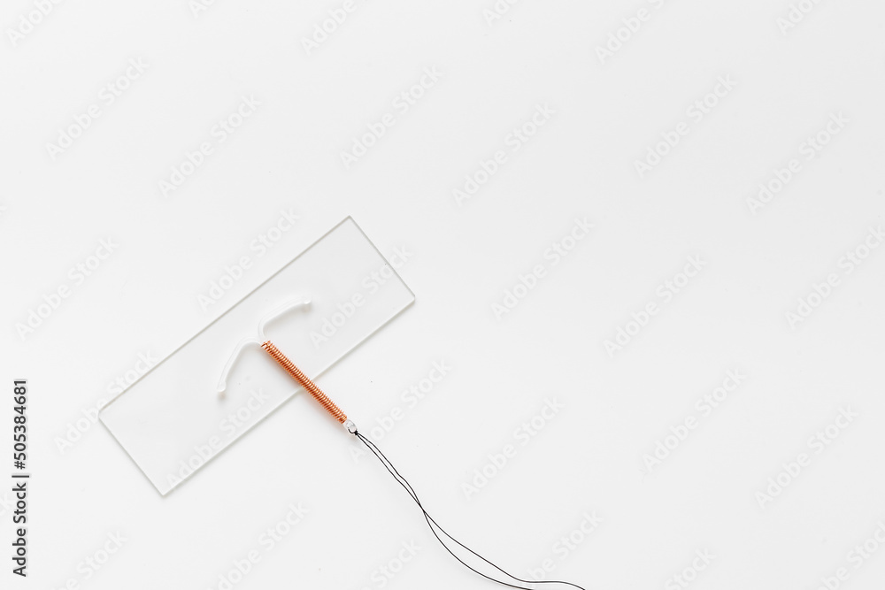 T-shaped copper contraceptive on medical glass. Hormone free contraception concept T-shaped copper contraceptive on medical glass. Hormone free contraception concept