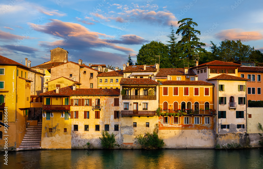 Bassano del Grappa, Veneto, Italy. Ancient italian houses on river Brenta. Panoramic view at old town with vintage buildings of Alpine mountains scenic sunset landscape.