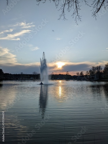 fountain in the middle of the lake at sunset