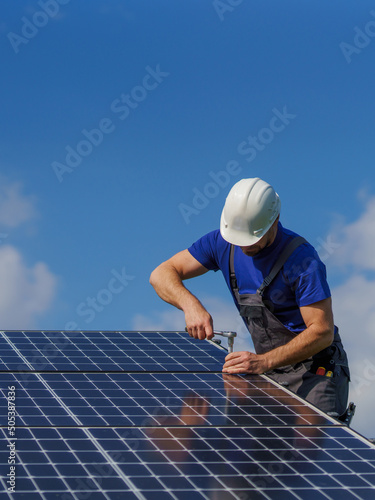 Foto Man worker installing solar photovoltaic panels on roof, alternative energy concept