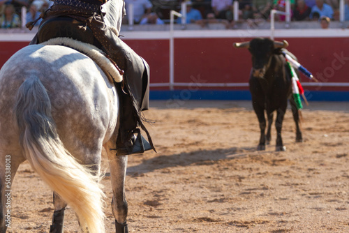 wounded bull chases a horse during a bullfight