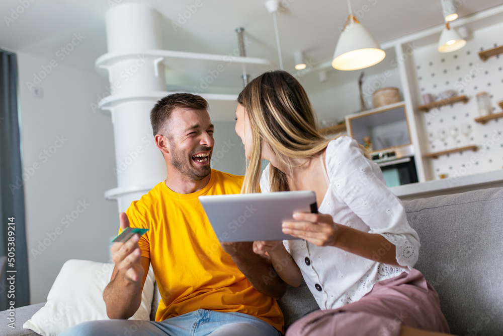 Happy young couple shopping online with digital tablet and credit card at home Happy young couple shopping online with digital tablet and credit card at home
