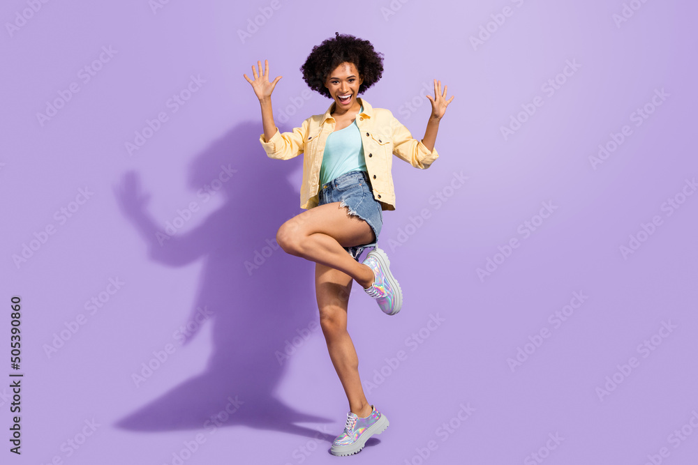 Photo of funny impressed woman dressed yellow jeans rising arms dancing isolated purple color background