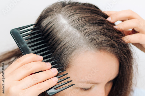 The girl combs the roots treated with a spray of dry shampoo on the roots of her hair.