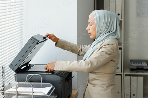 Konstfotografi Side view of modern young adult Muslim woman wearing hijab working in office mak