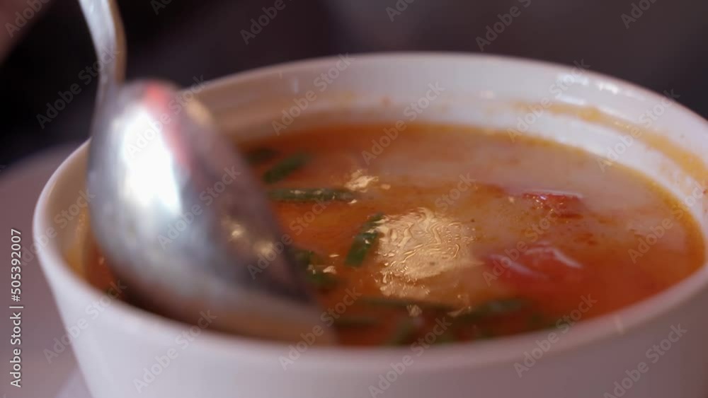 Women's hands stir the soup with a spoon. Extreme close-up of Asian soup with shrimp and seafood. Tom Yum - Asian dishes Women's hands stir the soup with a spoon. Extreme close-up of Asian soup with shrimp and seafood. Tom Yum - Asian dishes