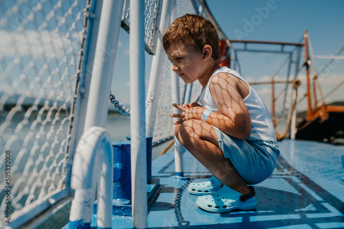 Little curious boy looking at water from motor boat.