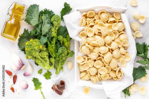 Orecchiette con cime di rapa ingredients typical of Apulia regional cuisine - homemade fresh pasta, turnip greens, chilli pepper, garlic and anchovy at the background. Flat lay, overhead view photo