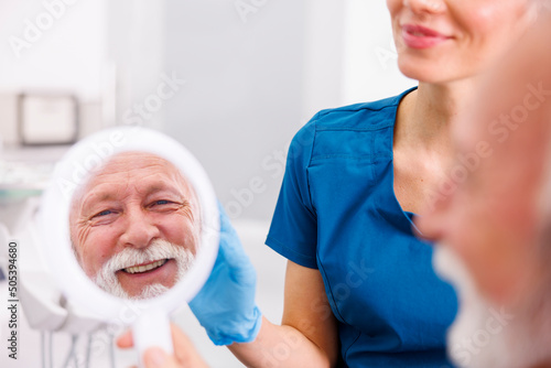 Patient looking in the mirror at dentist office smiling satisfied