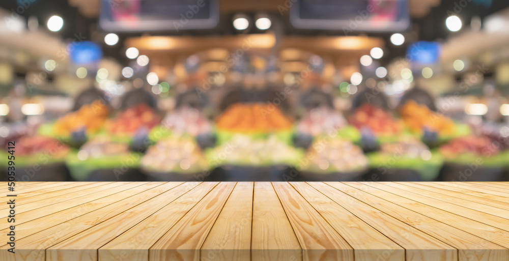 Empty wood table top with blur fruits in basket supermarket grocery store background