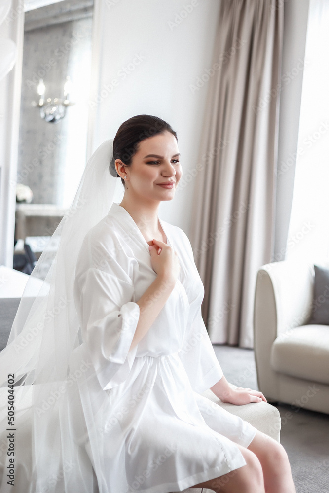 An adorable, gorgeous bride poses in a hotel room. Daylight, natural light, spacious room. An adorable, gorgeous bride poses in a hotel room. Daylight, natural light, spacious room.