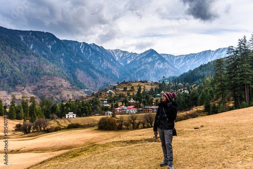 Young woman traveller looking towards the Himalayas mountains in Sainj Valley, Great Himalayan National Park, Himachal photo