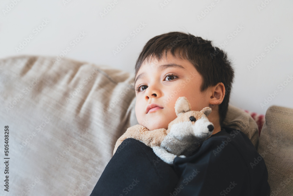 Portrait Young boy looking deep in thought,School Kid looking out with thinking face. Child with curious face sitting alone on sofa. Positive Child resting watching TV in living room Portrait Young boy looking deep in thought,School Kid looking out with thinking face. Child with curious face sitting alone on sofa. Positive Child resting watching TV in living room