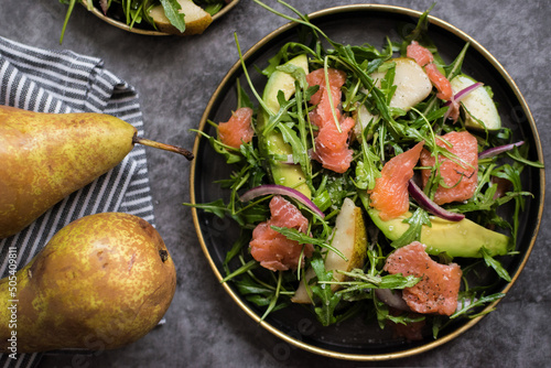 closeup of healthy avocado, salmon, and arugula salad on a plate