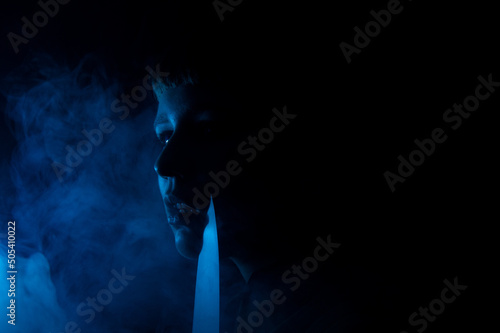 A gothic girl with a knife in smoke with dark background