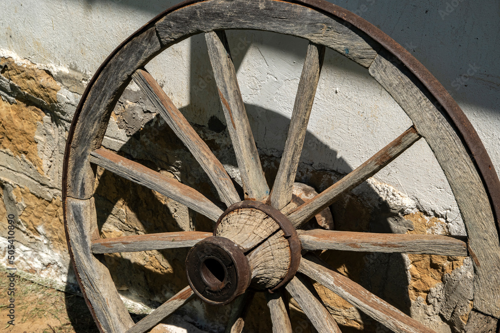 Old wooden wheel of country wagon as wall decoration of rural house