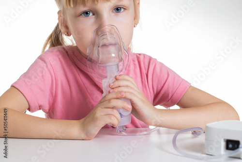 A 5-year-old caucasian girl is breathing into an inhaler at home. Treatment of cough and lung diseases in children, dilution of phlegm in the bronchi. photo