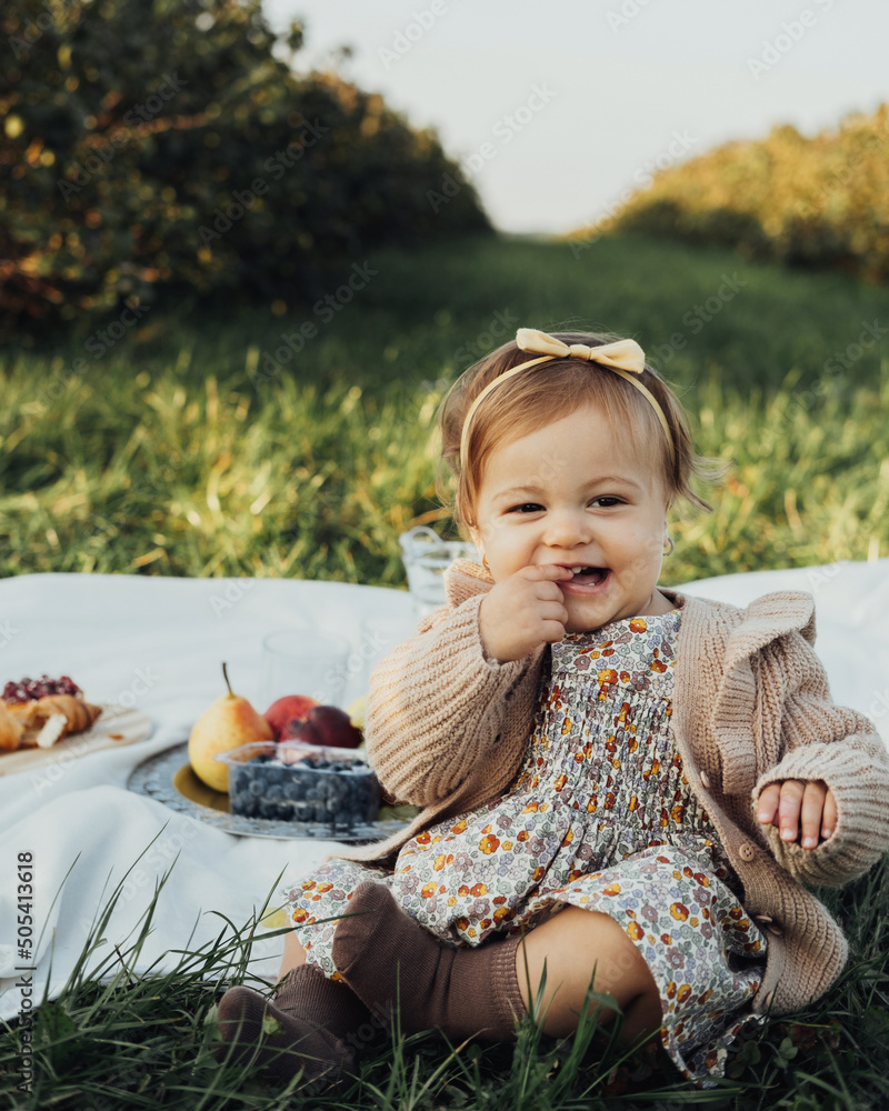 Φωτογραφία Vertical Portrait of Cheerful Little Baby Girl Sitting on a Plaid on Picnic Outd