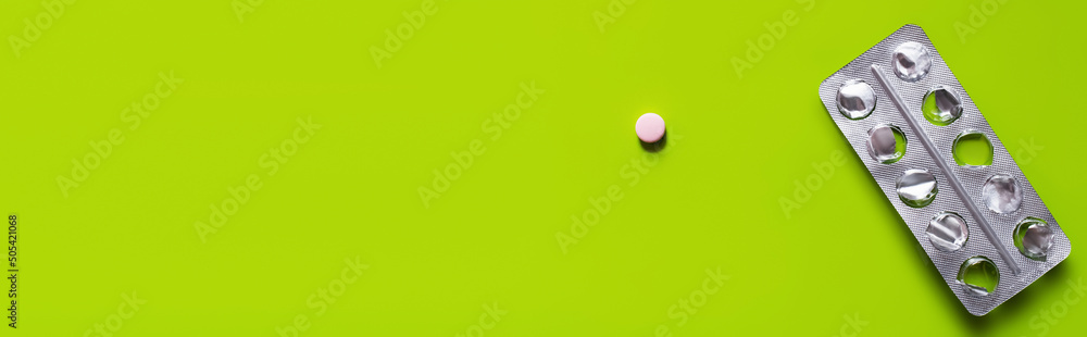 top view of used blister pack near round shape pill on green background, banner. - obrazy, fototapety, plakaty 