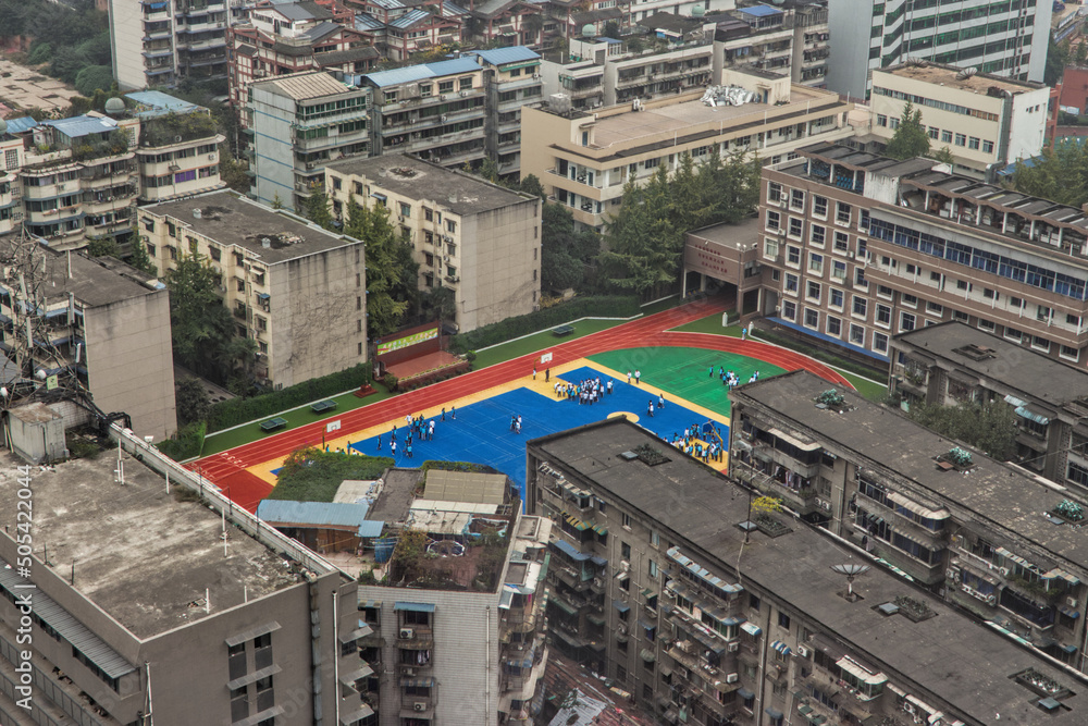 A colourful school playground contrasted by the surrounding grey, colourless buildings in China megacity