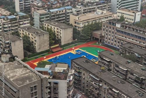 A colourful school playground contrasted by the surrounding grey  colourless buildings in China megacity