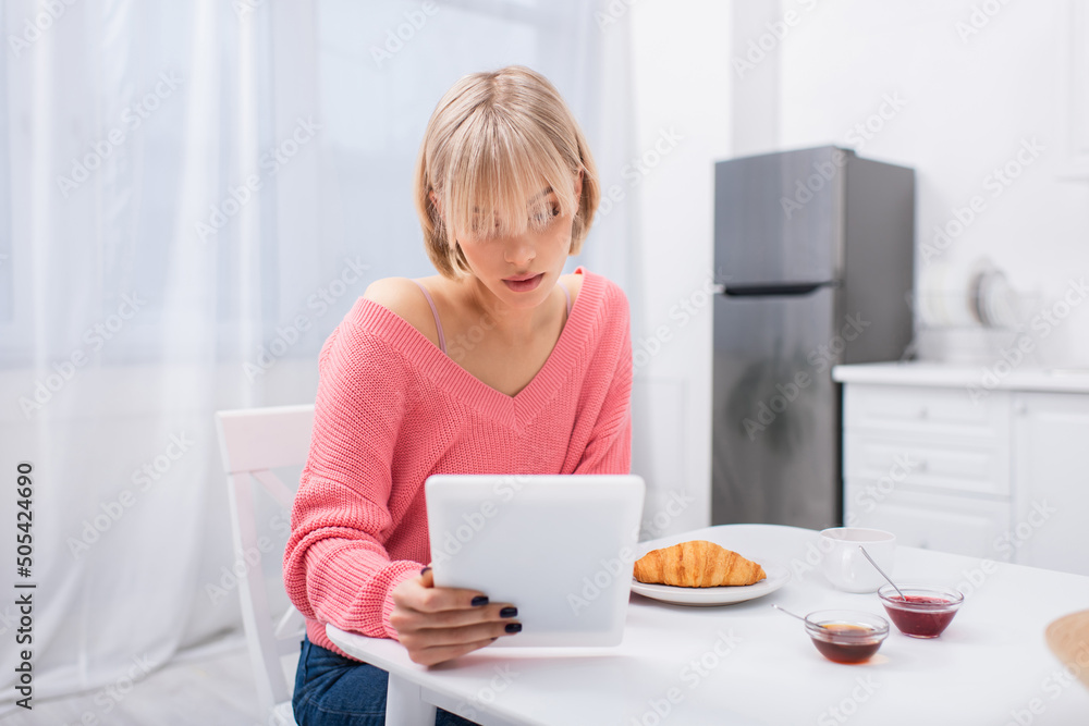 young blonde woman using digital tablet during breakfast. young blonde woman using digital tablet during breakfast.